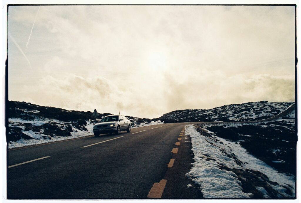 Coche circulando por una carretera de montaña con nieve
